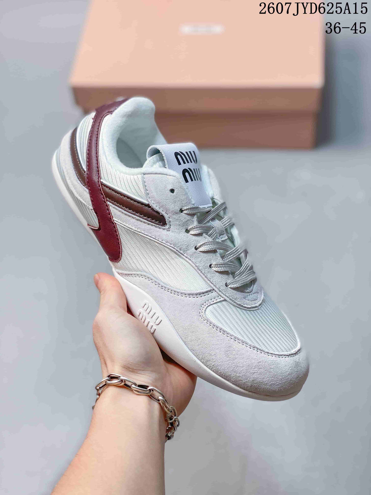 Angled side view of the white and burgundy Miu Miu sneaker showing the lace-up front, layered panels, side accent, and embossed branding near the outsole.
