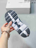 Underside view of a black and white sneaker showing segmented outsole sections and dark rubber tread.