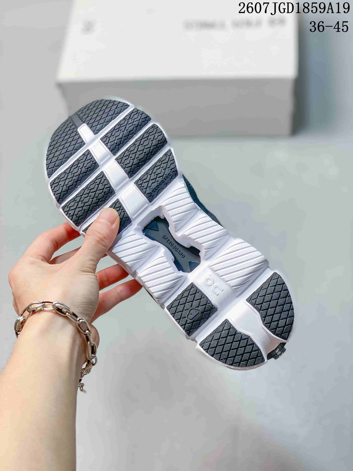 Underside view of a black and white sneaker showing segmented outsole sections and dark rubber tread.
