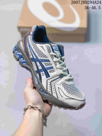 Three-quarter side view of the ASICS Gel-Kayano 14 sneaker showing the white and blue upper, layered side panels, and structured heel.