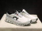 Front three-quarter view highlighting the white uppers, black toe accents, patterned laces, and open sole details.