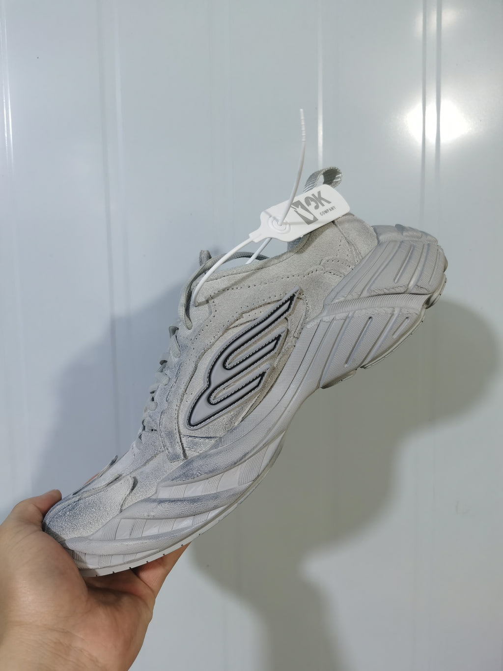 Underside and side view of the beige New Balance 9090 sneaker showing the textured outsole and layered upper construction.