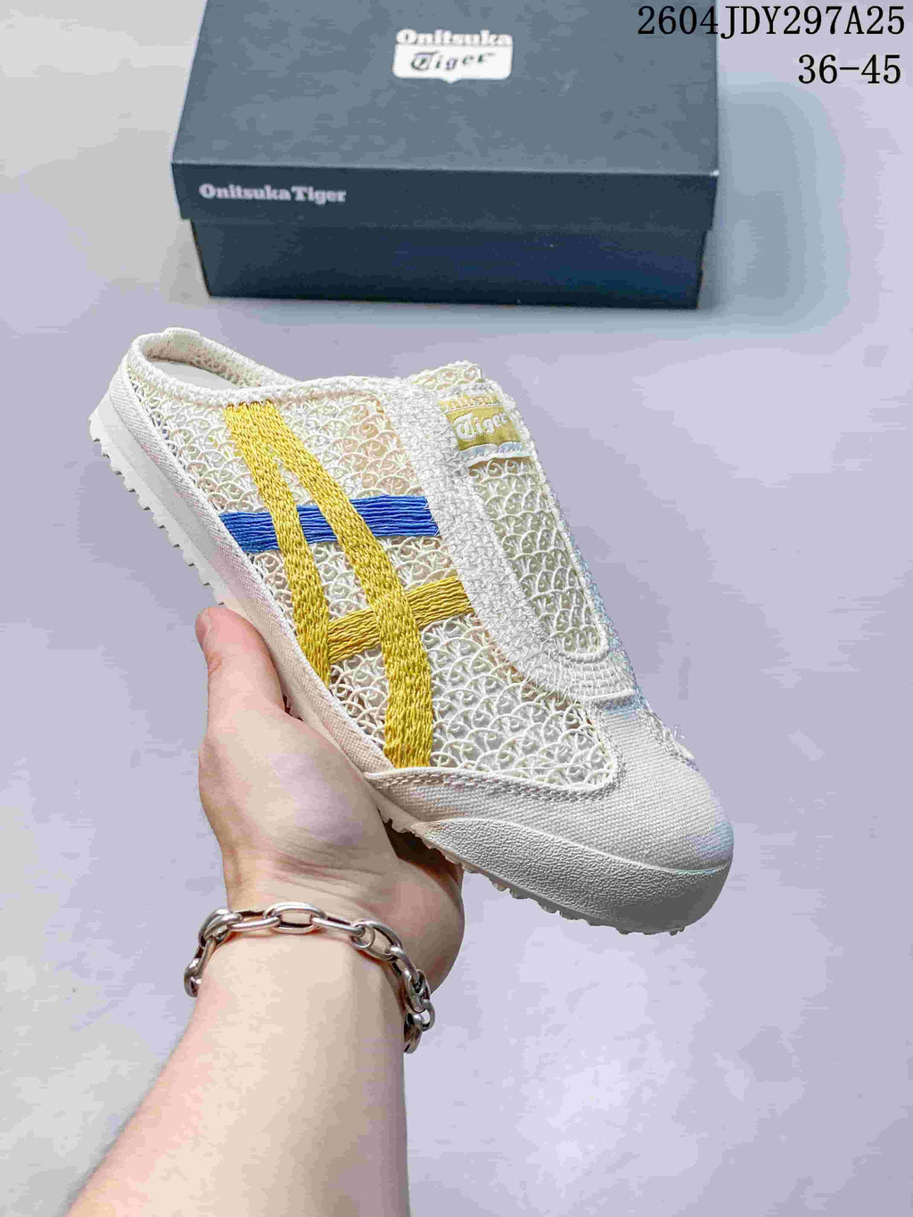 White Onitsuka Tiger Mexico 66 Sabot sneaker with yellow and blue side stripes, shown with its box; the image shows style code 2604JDY297A25 and size range 36–45.