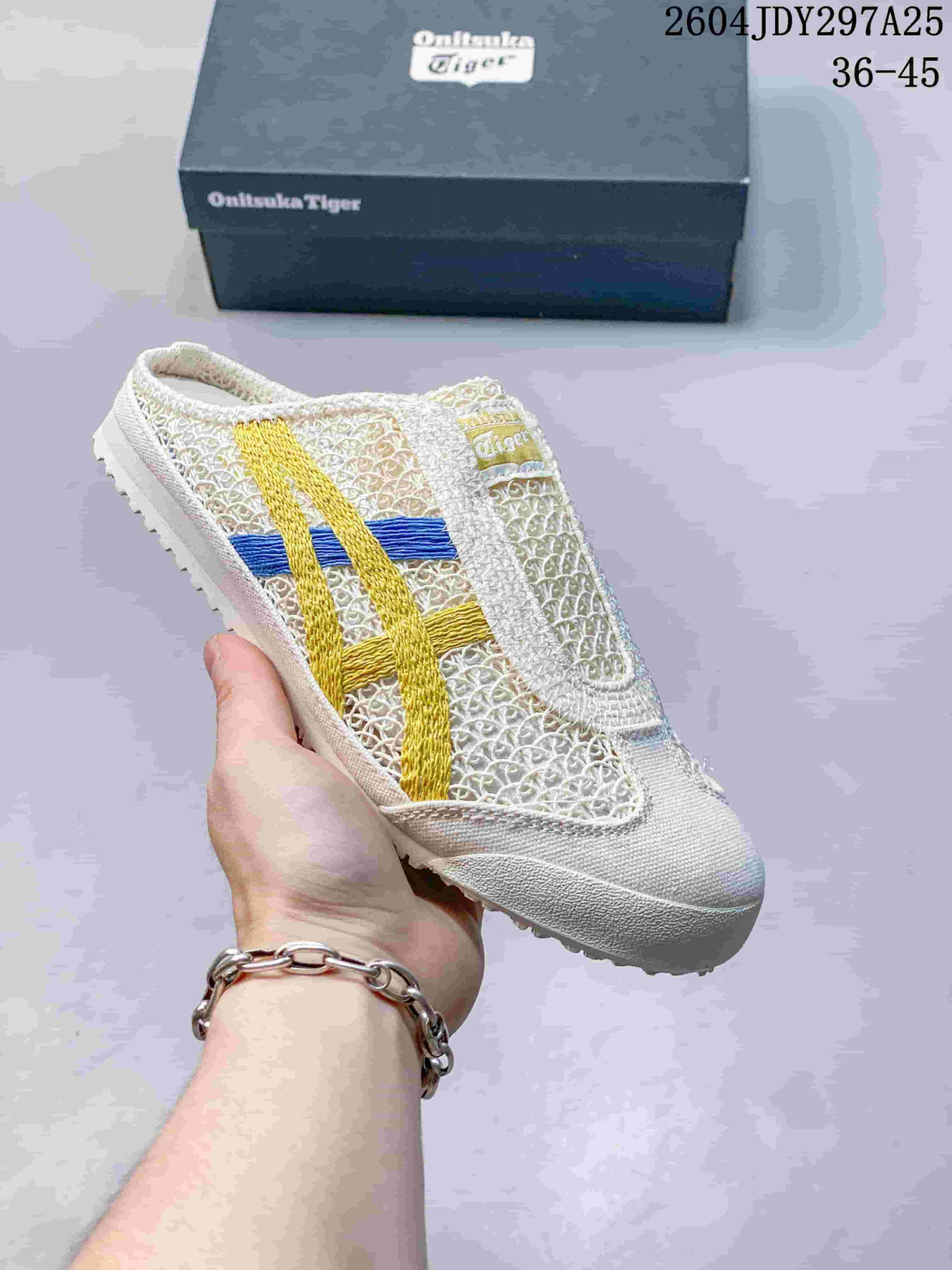 White Onitsuka Tiger Mexico 66 Sabot sneaker with yellow and blue side stripes, shown with its box; the image shows style code 2604JDY297A25 and size range 36–45.