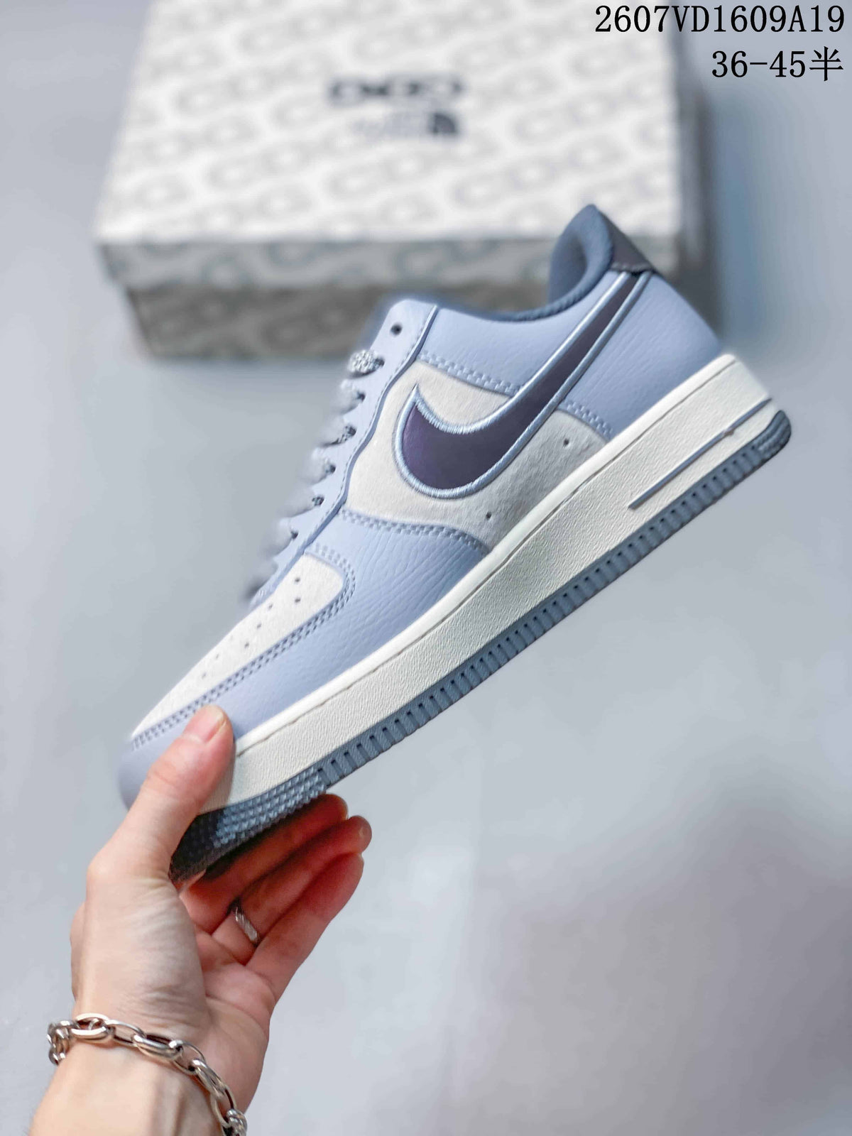 Side profile showing the pale blue-gray upper, contrasting Swoosh, speckled side panel, and layered sole.