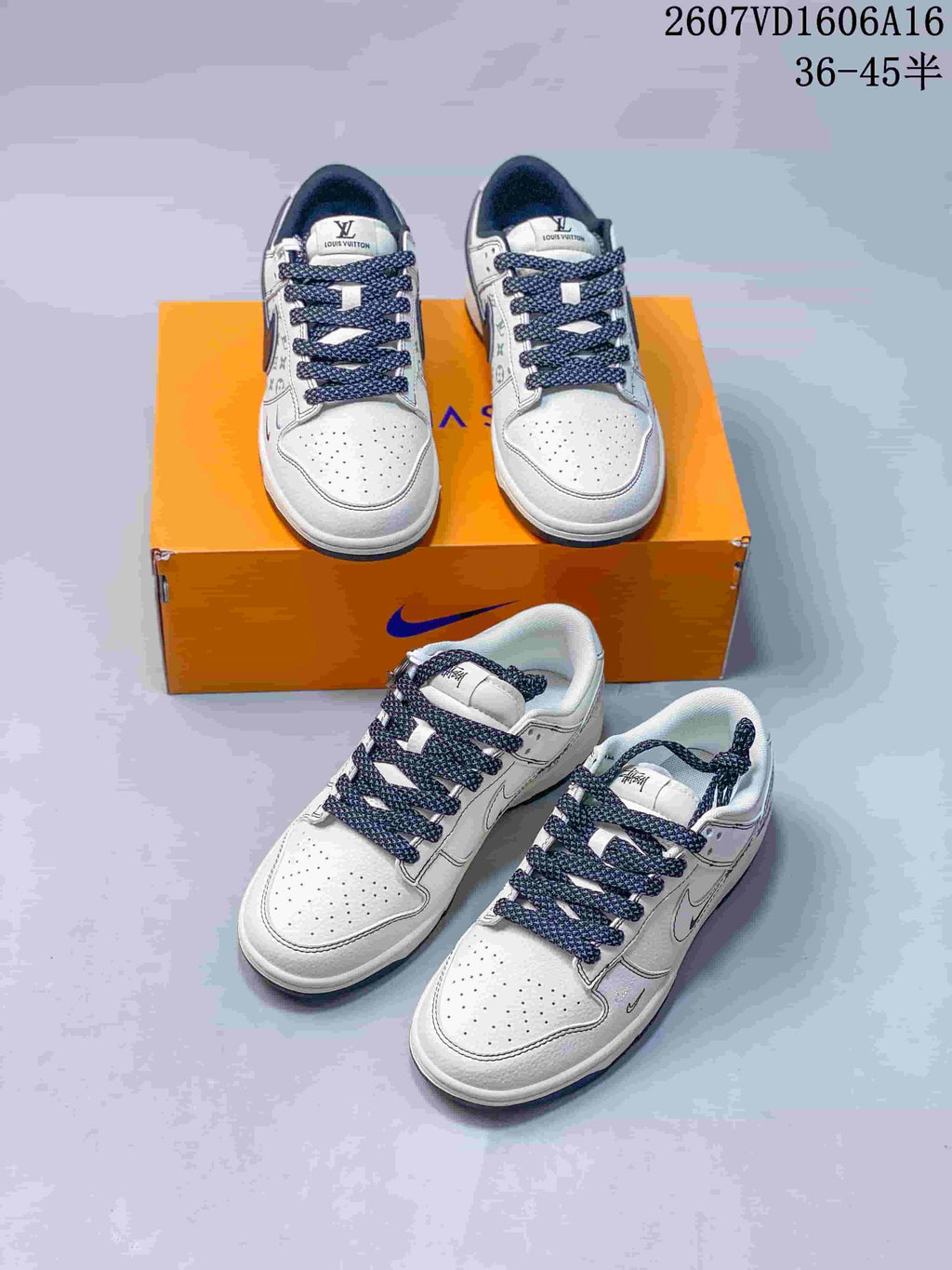 Four white low-top sneakers arranged around an orange shoe box, showing perforated toe boxes, dark navy laces, and patterned side panels.