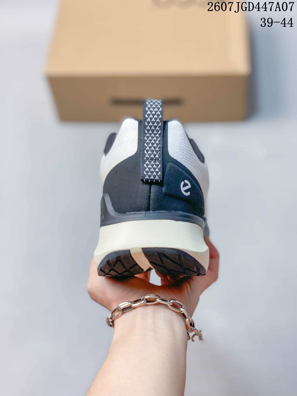 Rear view of the sneaker showing the navy heel panel, white midsole, patterned pull tab, and outsole tread.