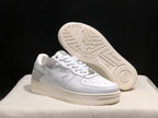 Angled view of the sneaker pair with one shoe lifted to reveal the patterned rubber outsole.