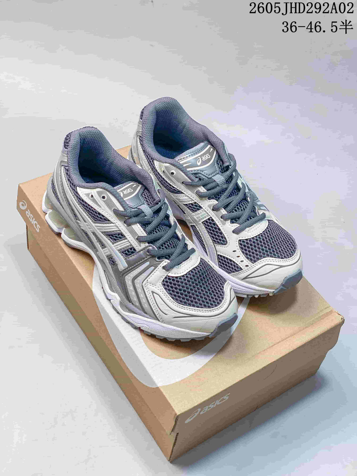 Pair of silver, charcoal, and white ASICS GEL-KAYANO 14 sneakers on a shoe box; image includes the printed size range 36–46.5.