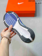 Underside view of the sneaker showing a segmented blue, white, and black rubber outsole.