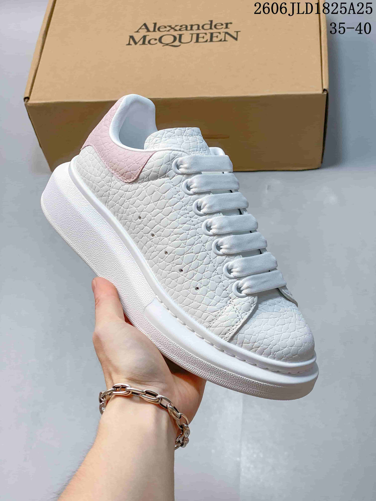 Side view of a white textured platform sneaker with a pink heel panel and wide laces.