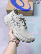 Light gray ASICS Gel-Nimbus 26 sneaker with a textile-style upper, dark outlined logo, white sculpted midsole, and visible PureGEL and FF BLAST+ markings.