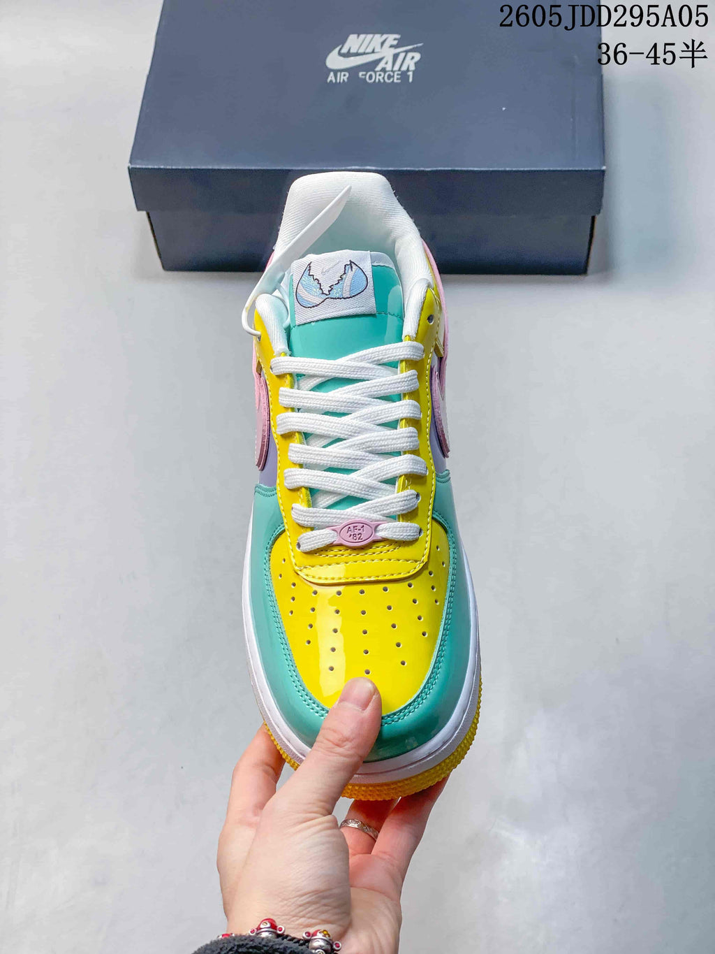Top view of the sneaker showing white laces, a turquoise tongue, yellow perforated toe box and multicolor paneling.