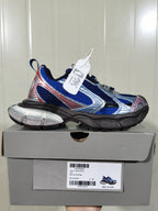 Royal blue, silver, black, grey, and pink low-top sneaker displayed on its box; the box label shows “REFLECTIVE/NW,” “ROYAL/GREY,” and size “C 37.”