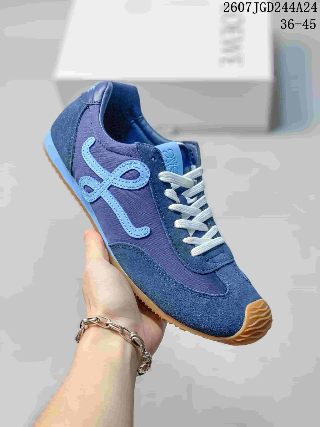 Angled side view of the blue Loewe sneaker showing the light-blue side motif, layered upper, white laces, and gum-colored outsole.