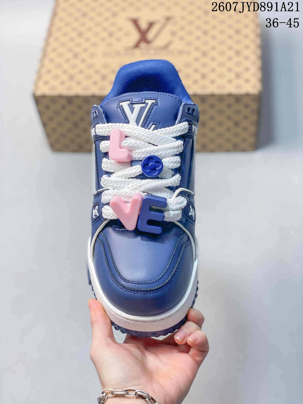Top view of the blue sneaker showing the rounded toe, white laces, and pink and blue decorative lace charms.
