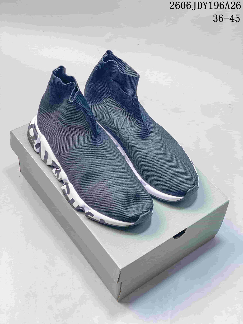 Pair of dark gray Balenciaga sock-style sneakers with white sculpted midsoles displayed on a shoebox; style code 2606JDY196A26 and size range 36–45 are visible.