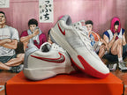 Pair of white and red Nike basketball shoes displayed from an angled side view