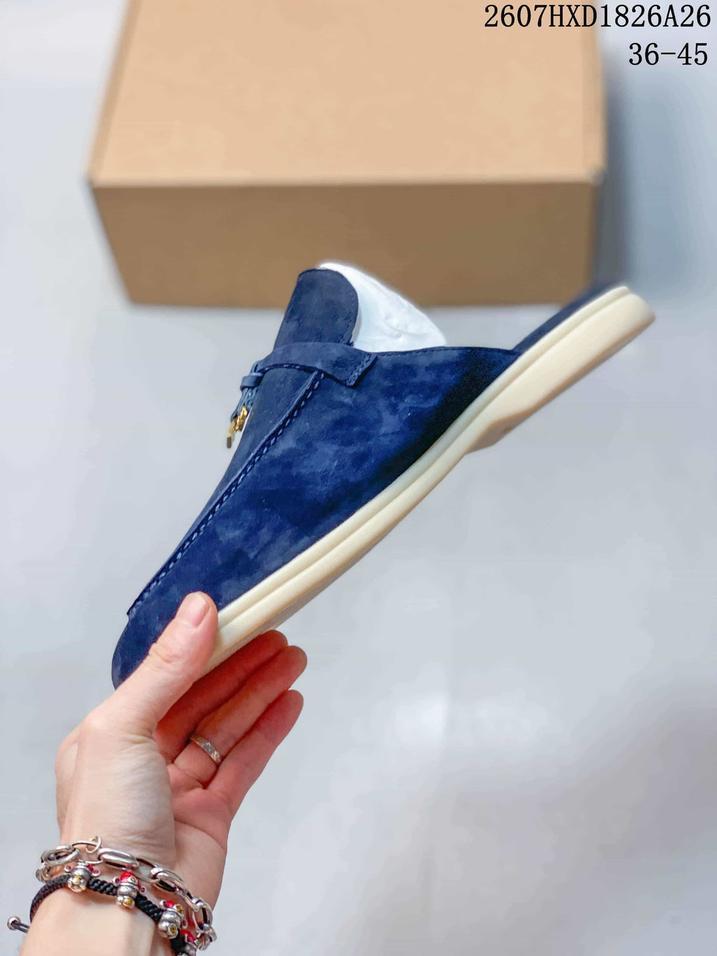 Side profile of a navy loafer mule showing the low cream-colored sole, open heel, and vamp strap.