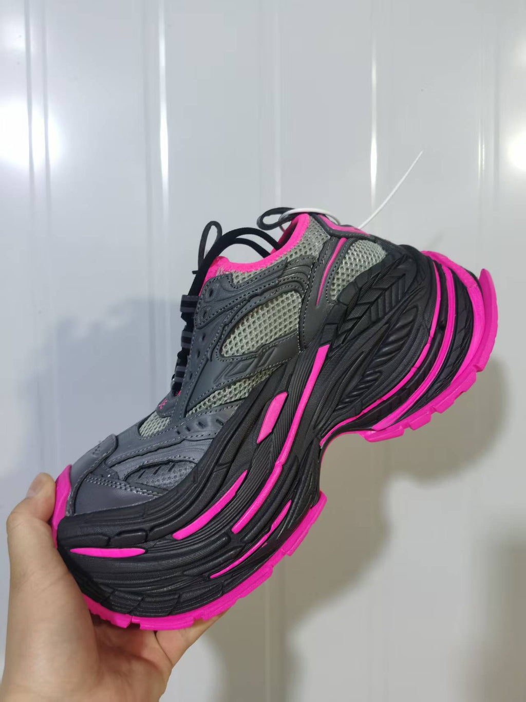 Angled rear-side view showing the mesh panels, black layered sole, and pink outsole details.