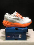 Side view of white Brooks Glycerin 21 sneakers with orange laces and orange soles on a shoe box.