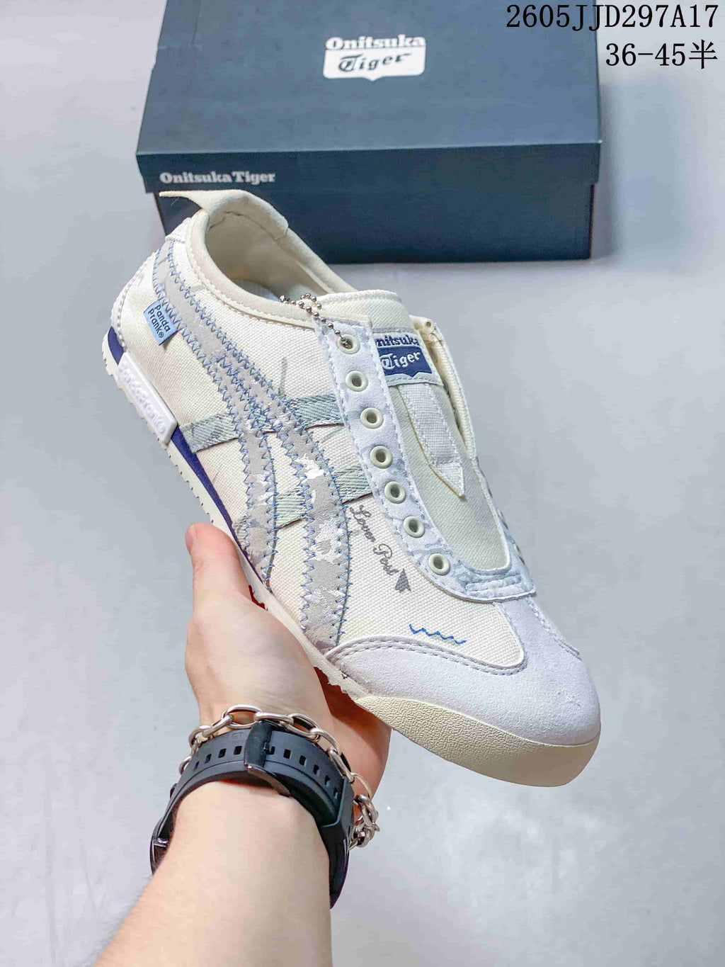 Angled side view showing the off-white upper, pale blue side stripes, blue heel accent and textured outsole; JJD297A17 and the size range 36–45.5 are visible.