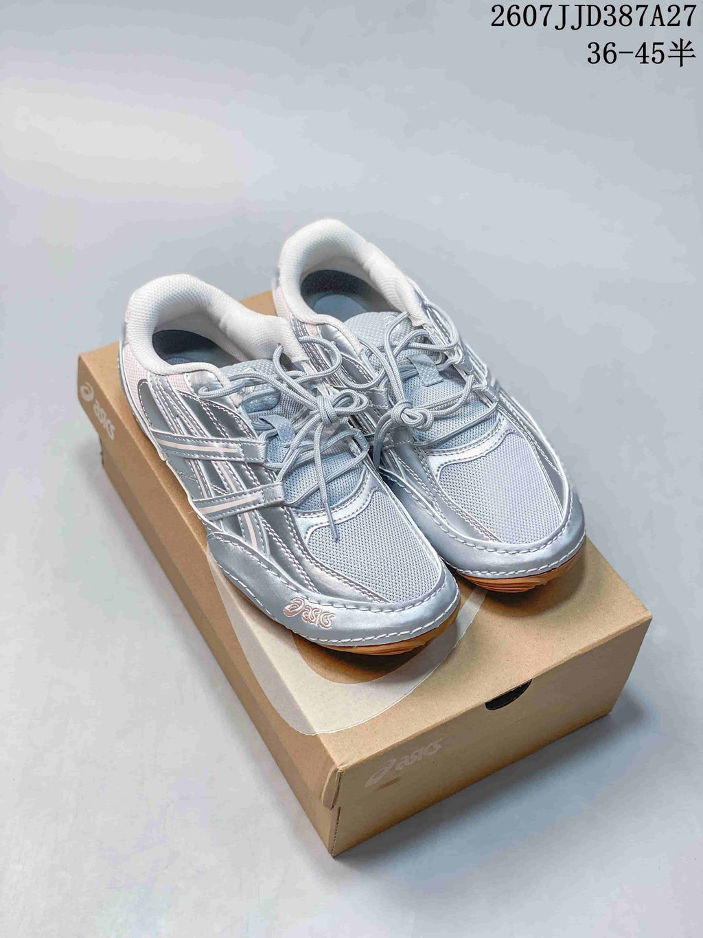 Pair of silver ASICS Hypersync low-top sneakers displayed on an ASICS shoe box.