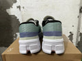 Rear view of sage-green On Running shoes with purple heel bands and white sculpted soles.