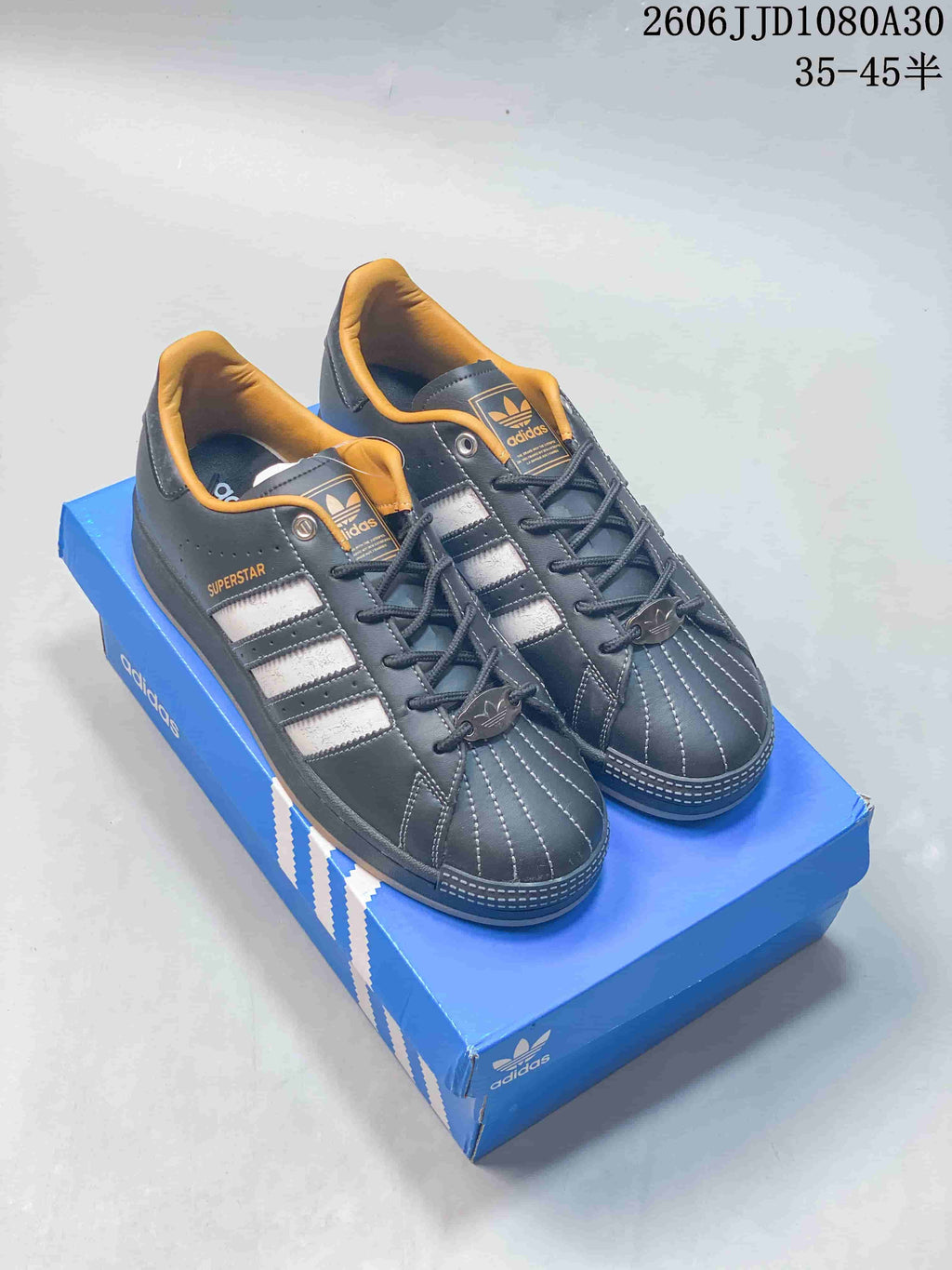 Pair of charcoal adidas Originals Superstar low-top sneakers with contrasting stripes and gum-colored soles