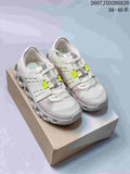 Pair of white and light gray On sneakers with neon yellow lace details displayed on a shoebox.