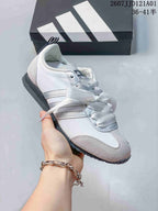 Close-up of a white and silver JOG 2.0 sneaker with ribbon laces