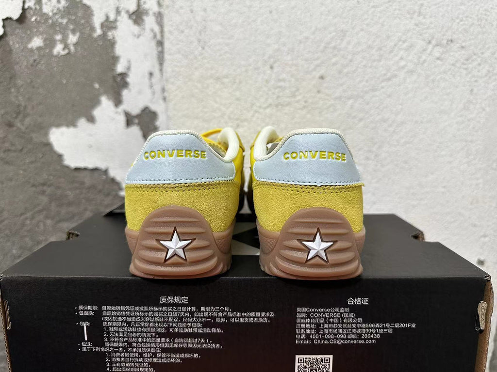 Rear view of yellow Converse training-style shoes with light-colored heel panels and gum-colored soles.