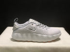 Single white sneaker in side profile, showing the textured upper, side logo and sculpted white midsole.