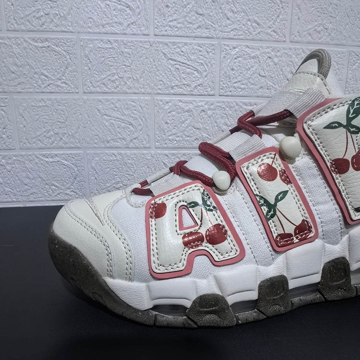Close-up of the sneaker upper, burgundy laces, and cherry print