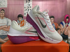 Pair of white Nike running shoes with pink accents and purple-toned soles, shown from the side