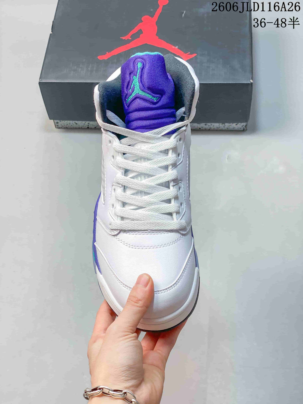 Front view of a white high-top sneaker with purple tongue and white laces