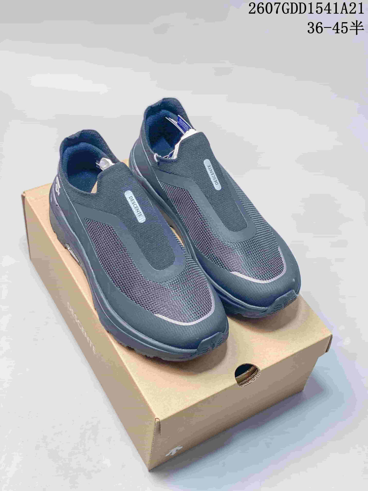 Pair of dark DESCENTE slip-on sneakers displayed on a shoebox, showing the front and upper design.