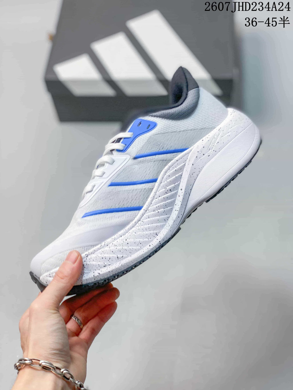 Side profile showing the white upper, blue accents and speckled layered midsole.