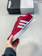 Side profile of the red sneaker with white stripes, lace eyelets, and a white rubber sole.