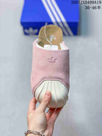 Front view of the pink adidas Adimule mule showing the embossed Trefoil logo, perforated upper, and off-white ribbed toe guard.