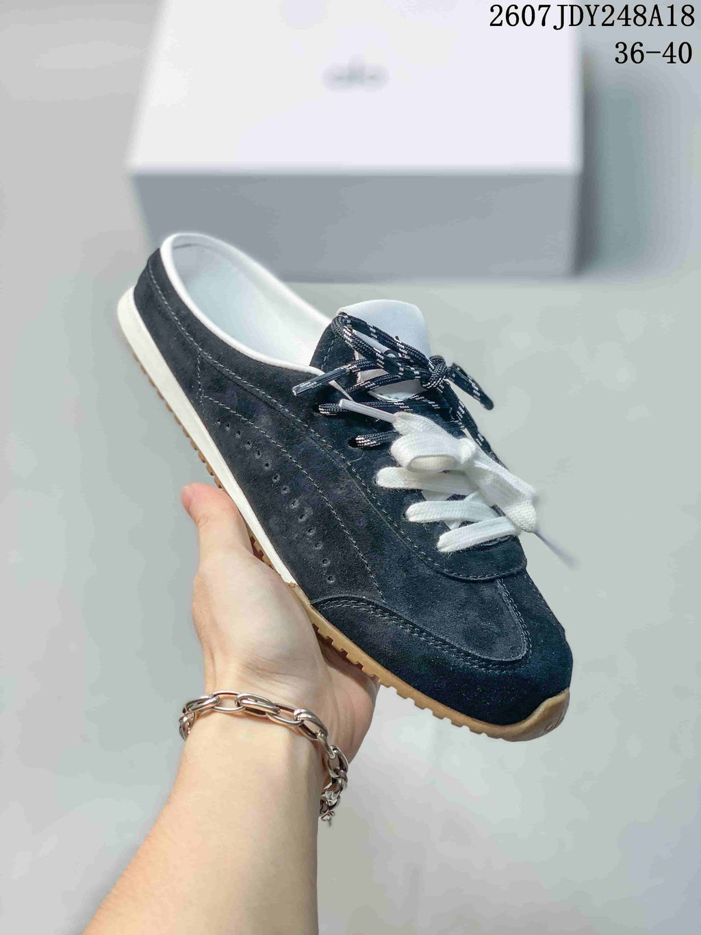 Side view of a navy alo mule sneaker showing the open heel, perforated side panel and gum-colored outsole.