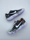 Pair of black Nike basketball shoes with white Swoosh logos, white laces, red collar accents, brushstroke graphics, and light-colored ridged outsoles.