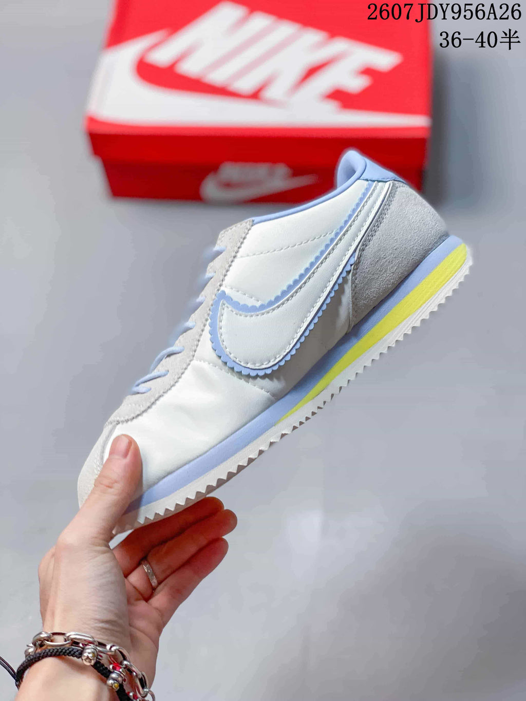 Side view highlighting the white upper, light blue Swoosh trim, and yellow midsole detail.