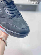 Close-up of the black sneaker toe box and gray laces, showing layered stitching and the dark outsole.