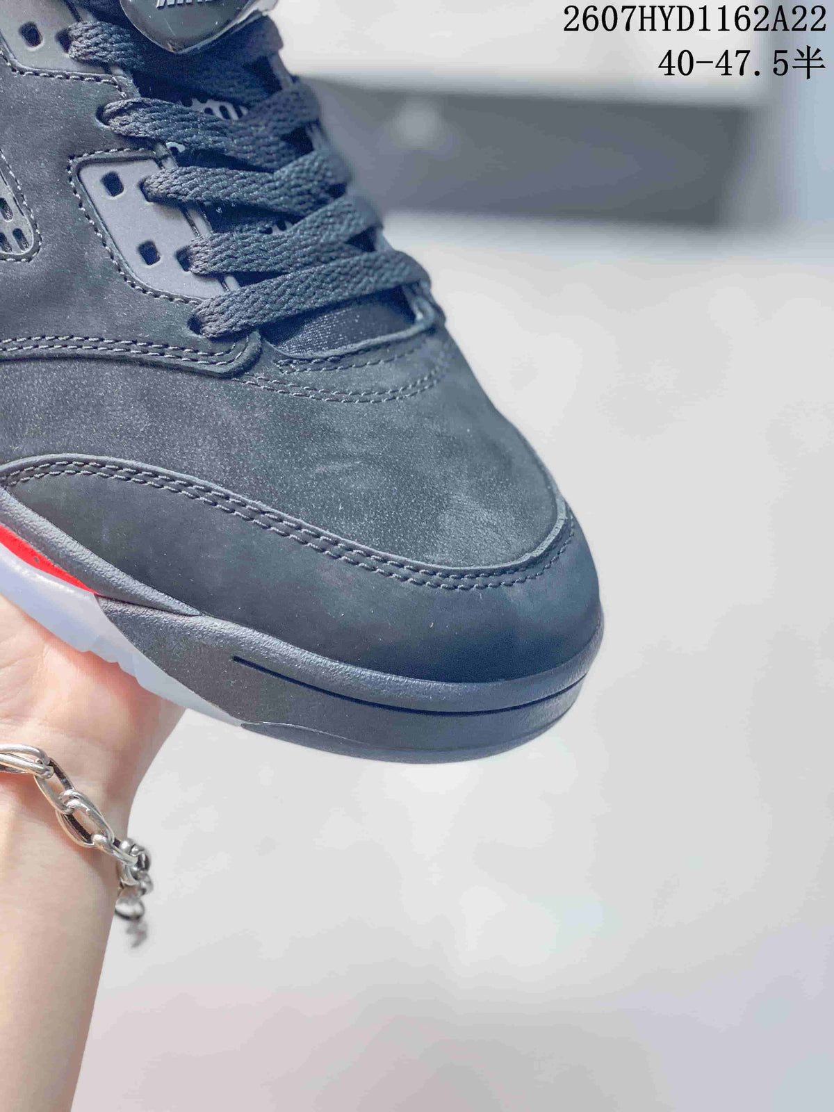 Close-up of the black sneaker toe box and gray laces, showing layered stitching and the dark outsole.