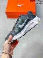 Side profile of the gray low-top sneaker showing the white Nike Swoosh, mesh-textured upper, white midsole, and neon green outsole detail.