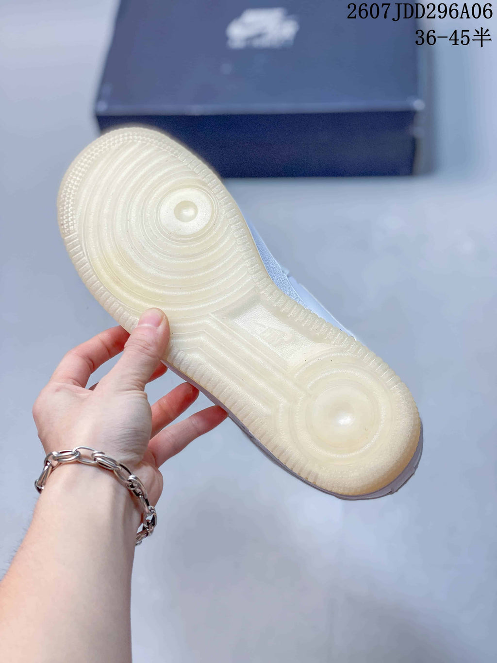 View of the translucent gum-colored outsole with circular traction details and a shoe box in the background.