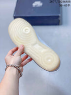 View of the translucent gum-colored outsole with circular traction details and a shoe box in the background.