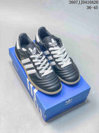 Pair of black and white Adidas Samba sneakers displayed on a blue shoebox.