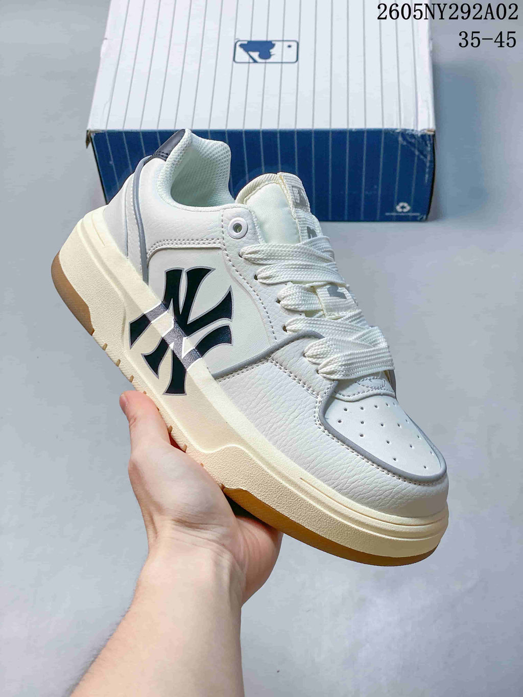Angled side view of the white and cream MLB sneaker showing black side branding, white laces, and a gum-colored outsole.